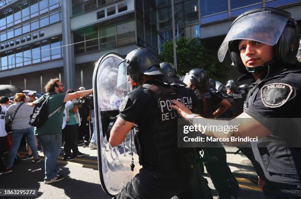 Person shouts as police officers stand guard during a demonstration against President Javier Milei and recent announcements by Minister of Economy...