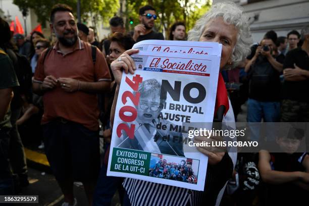 Woman holds a newspaper with a message against the economic adjustment during the first demonstration against the new government of Javier Milei at...