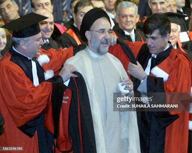 The dean of the Lebanese University Ibrahim Qobaissi and an unidentified colleague help Iranian President Mohammad Khatami into his robes during a...