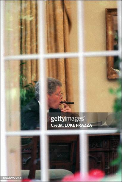 -- File photo dated 27 May 1993 in Washington, DC. Shows US President Bill Clinton chewing on a cigar in the Oval Office of the White House as he...
