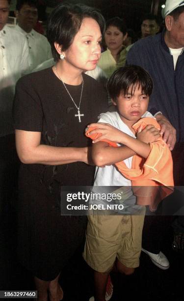 President Gloria Arroyo accompanies a young boy from the MV San Nicolas which collided with a bigger passenger ferry at a naval base in Manila 25 May...