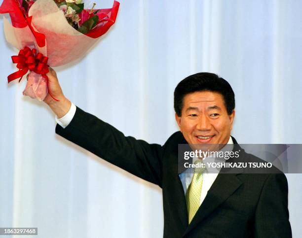 Visiting South Korean President Roh Moo-Hyun waves a bouquet as he enters a Tokyo hotel room for a reception with South Korean residents in Japan, 08...