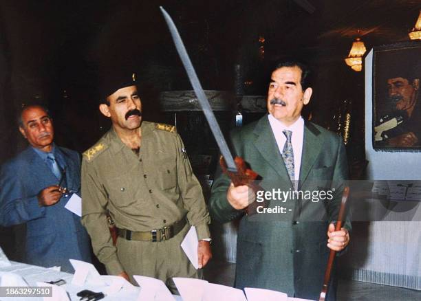 This 11 August 2002 file photo released by the Iraqi state news agency INA shows then Iraqi president Saddam Hussein with a sword presented to him as...