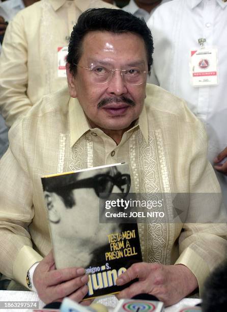 Detained former Philippines president Joseph Estrada displays an autobiography of slain opposition senator Benigno Aquino during a news conference...