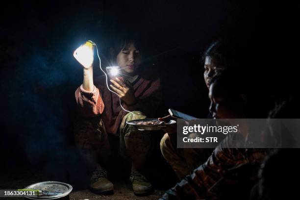 This photo taken on December 8, 2023 shows female members of the Mandalay People's Defense Forces cooking food by a stove at their base camp in the...