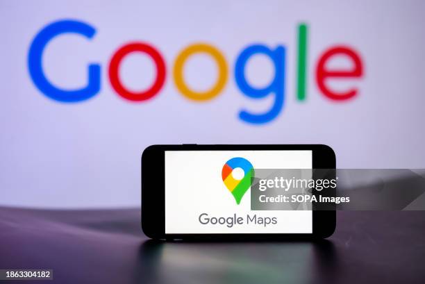 In this photo illustration, the Google Maps logo is seen displayed on a mobile phone screen with Google Logo in the background.