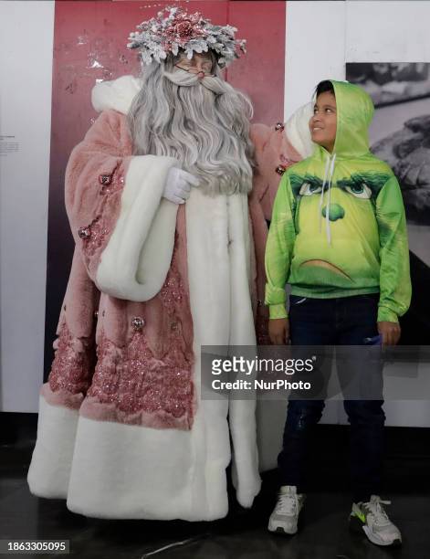 Jose Miguel Moctezuma Gonzalez, a street artist specializing in human statuism and makeup, is dressed as Santa Claus and is interacting with a person...