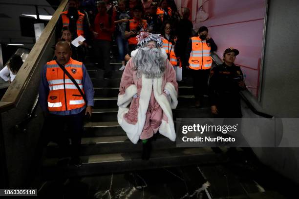 Jose Miguel Moctezuma Gonzalez, a street artist who specializes in human statues and make-up, is dressed as Father Christmas and is being escorted by...
