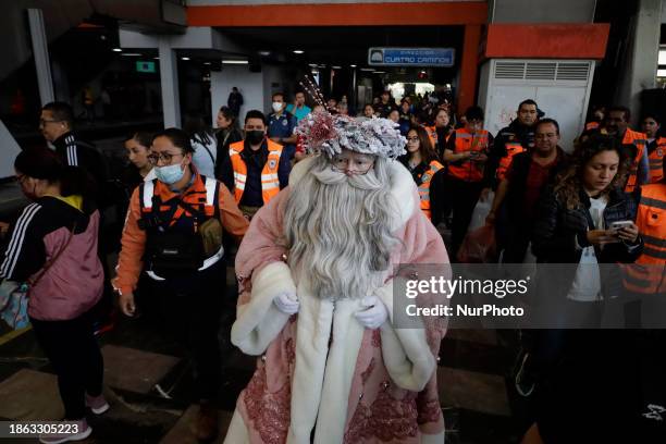 Jose Miguel Moctezuma Gonzalez, a street artist who specializes in human statues and make-up, is dressed as Father Christmas and is being escorted by...