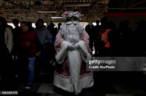 Jose Miguel Moctezuma Gonzalez, a street artist who specializes in human statues and make-up, is posing as Father Christmas and walking through...