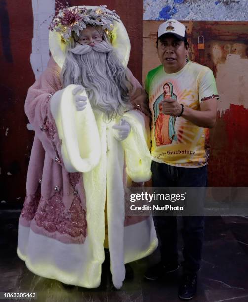 Jose Miguel Moctezuma Gonzalez, a street artist specializing in human statuism and makeup, is dressed as Santa Claus and is interacting with a person...