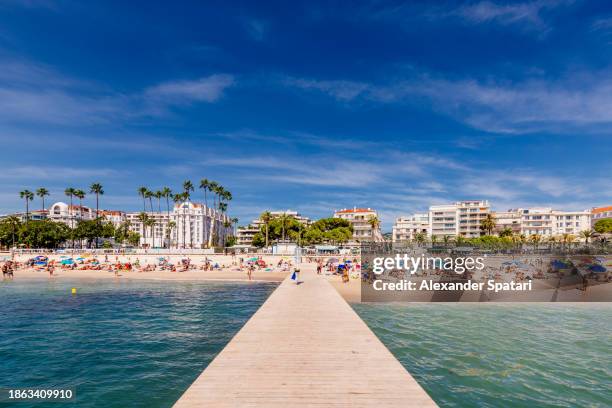 beach along boulevard de la croisette with crowds of tourists on a sunny summer day, côte d'azur, france - region provence alpes côte dazur stock-fotos und bilder