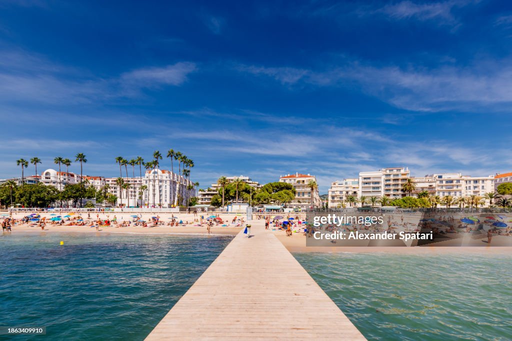 Beach along Boulevard de la Croisette with crowds of tourists on a sunny summer day, Côte d'Azur, France