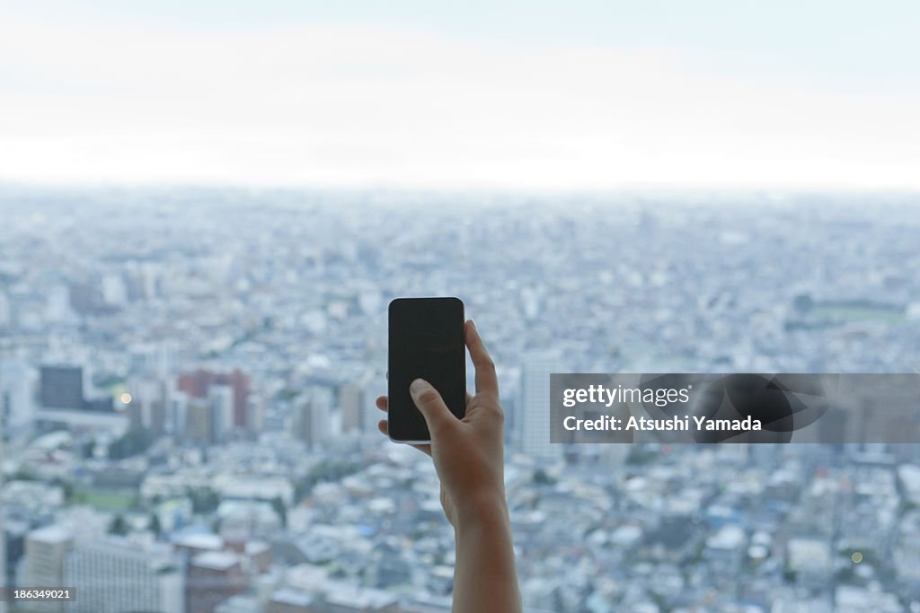 Young woman accessing city with smartphone