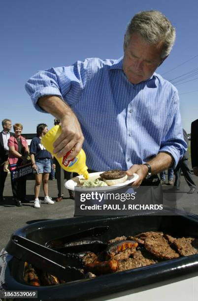President George W. Bush adds a little mustard to a hamburger after stopping on his bus tour through Missouri at the Bomag manufacturing plant, to...