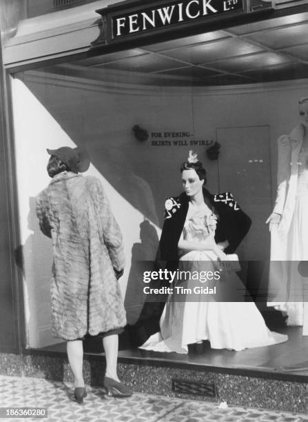 Woman looking at a window display of fashions at the Fenwick department store in Bond Street, London, May 1939. Original publication: Picture Post -...