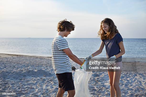two people collecting trash on beach - responsibility stock-fotos und bilder