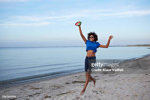 young woman jumping, catching ball on beach - woman catching stock pictures, royalty-free photos & images
