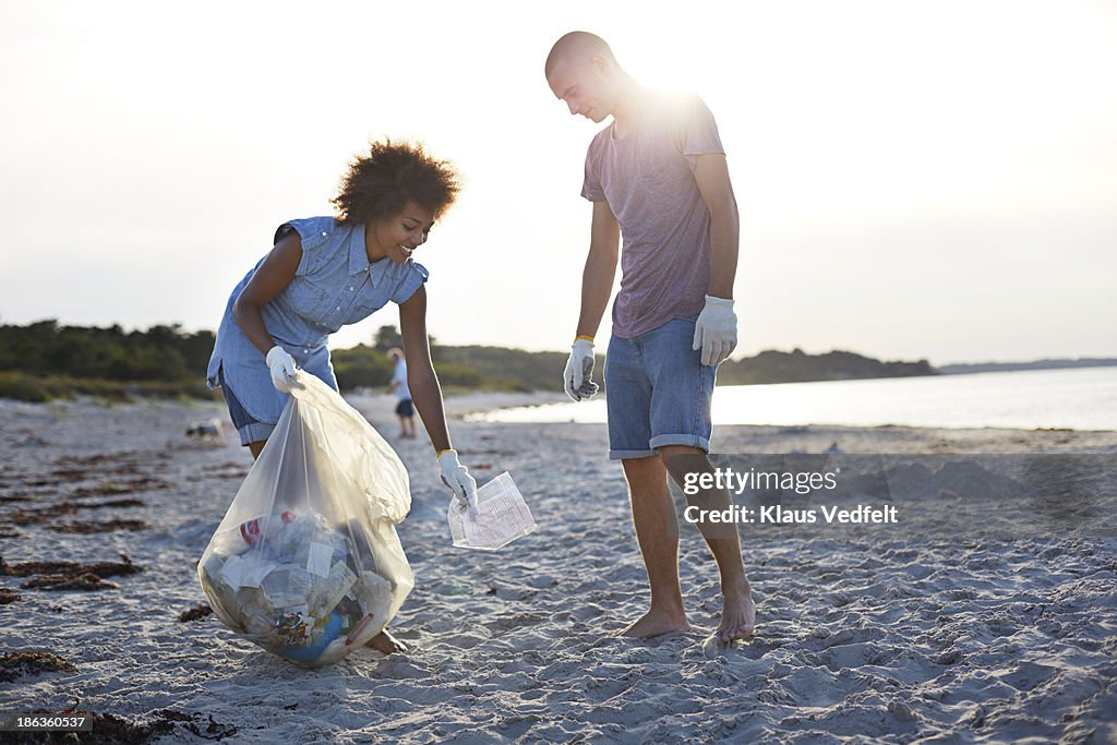 Two people collecting trash on beach
