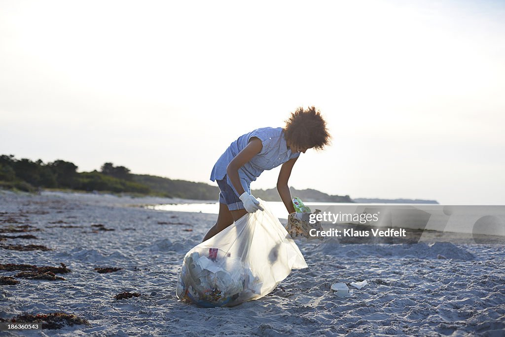 Young woman collecting trash on beach