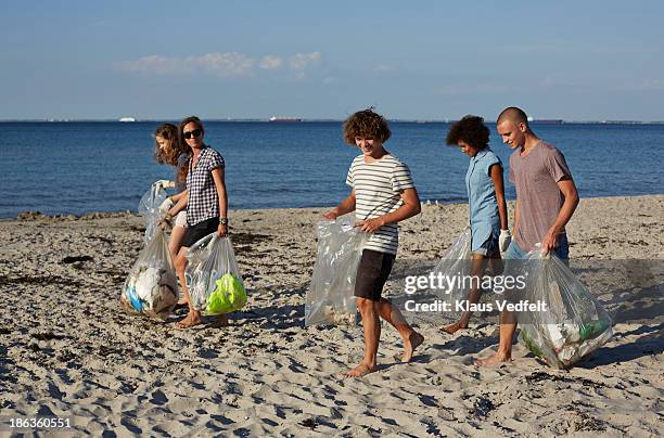 group people collecting trash on beach - volunteer beach photos et images de collection