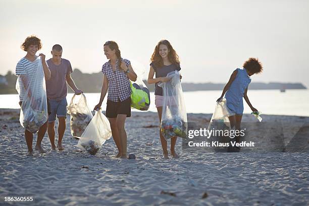 group of people walking with trashbags on beach - volunteer beach stock-fotos und bilder