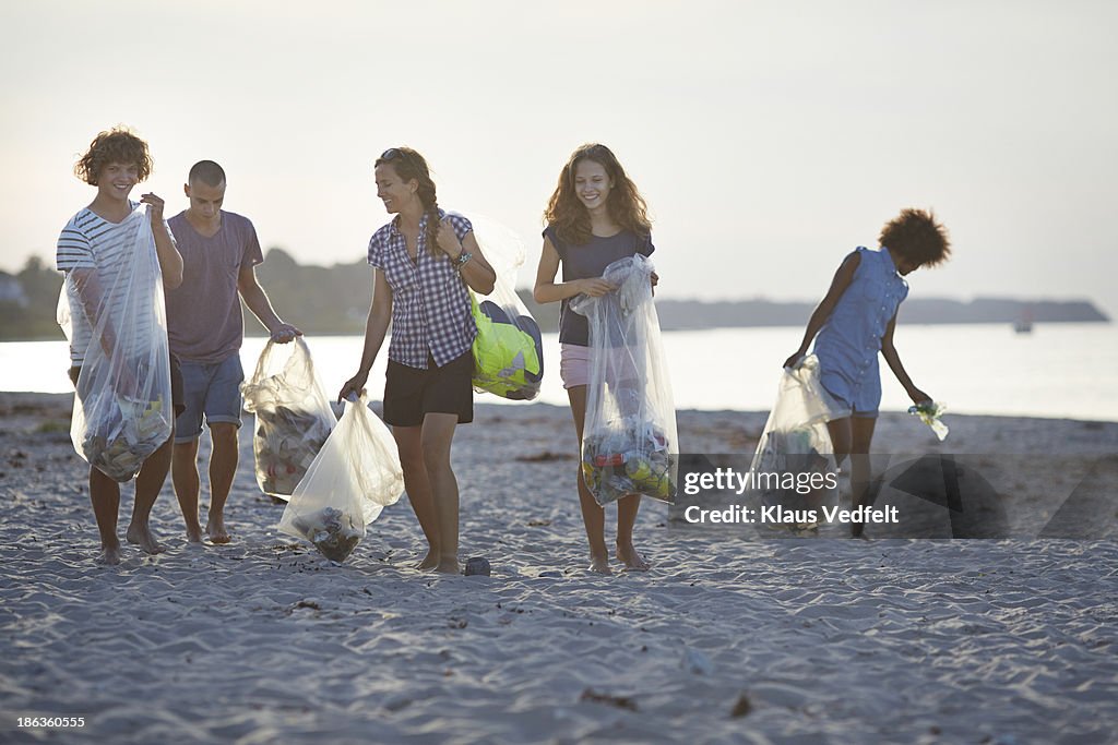 Group of people walking with trashbags on beach