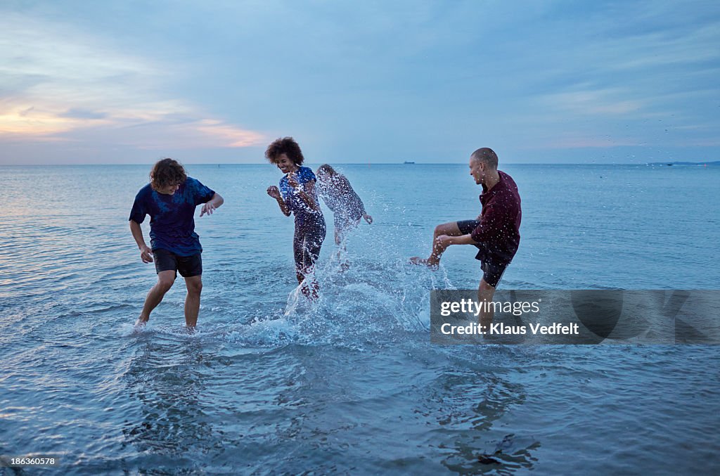 Teens kicking water at each other in the ocean