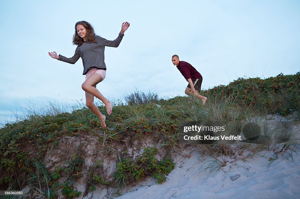 Teen girl jumping from sand dune