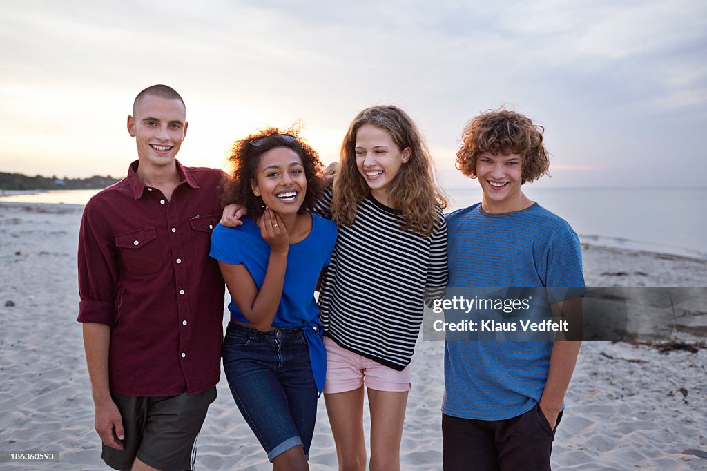 Group of teens with arms around each other & laugh