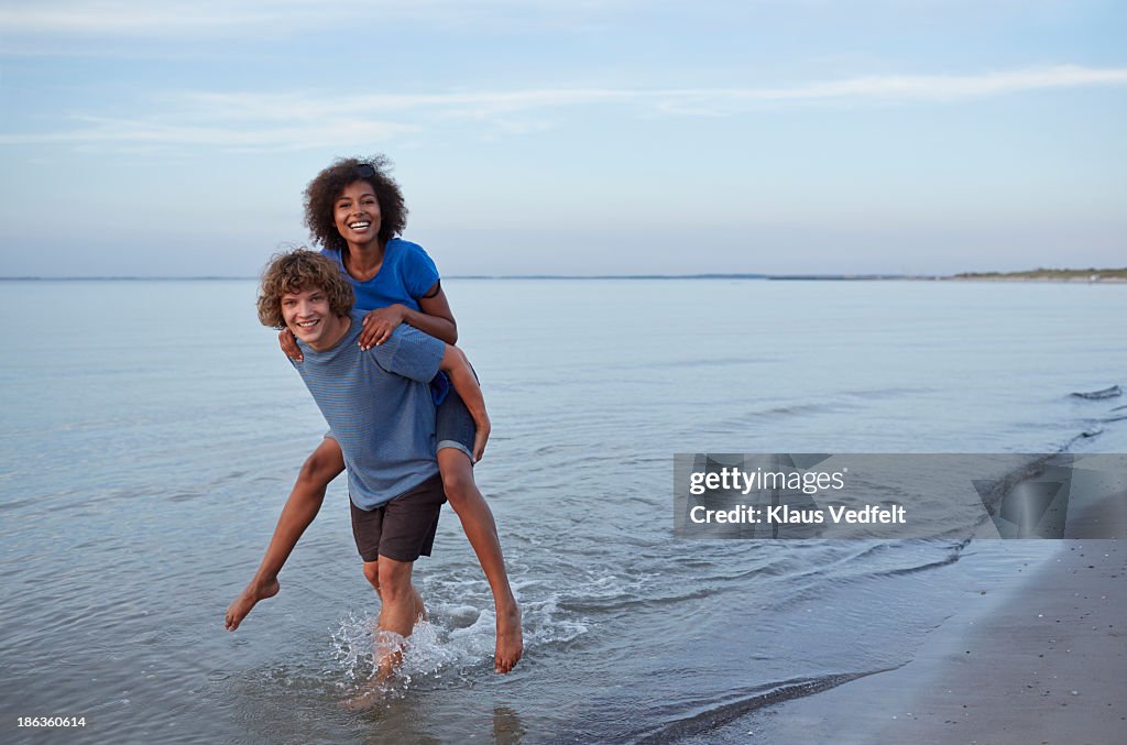 Young man carrying girlfriend on the back in ocean