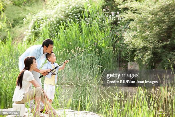 cheerful chinese family fishing in a park - father son water park stockfoto's en -beelden