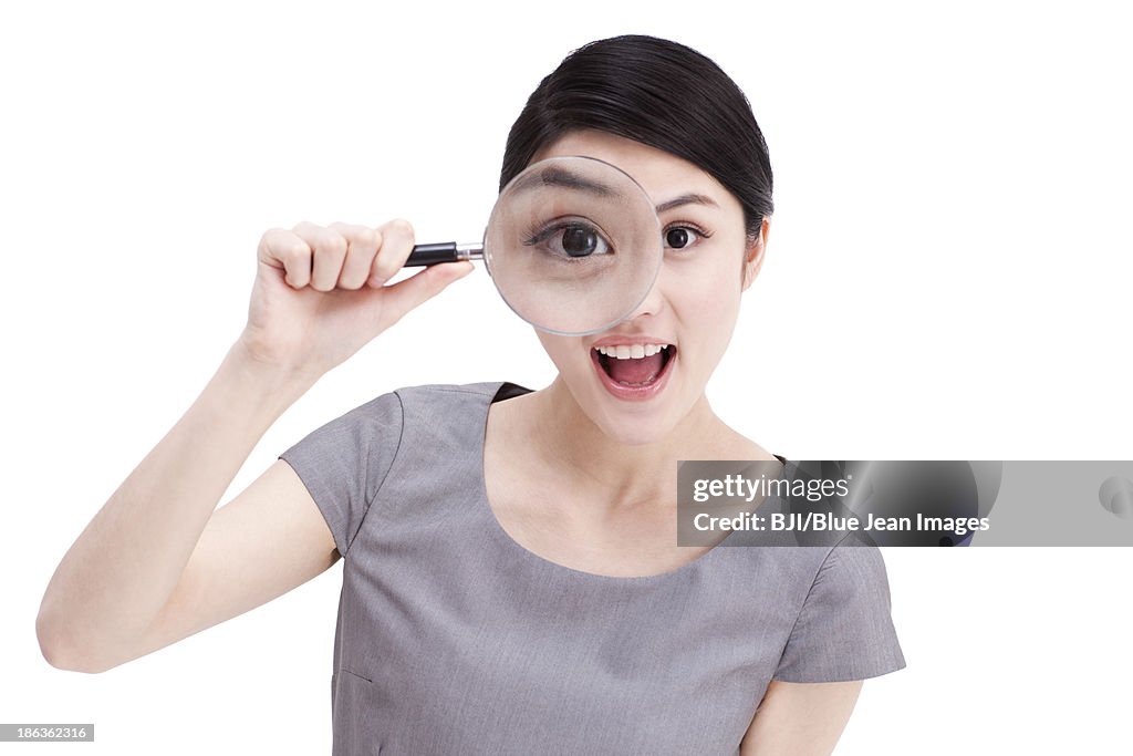 Young businesswoman looking through magnifying glass