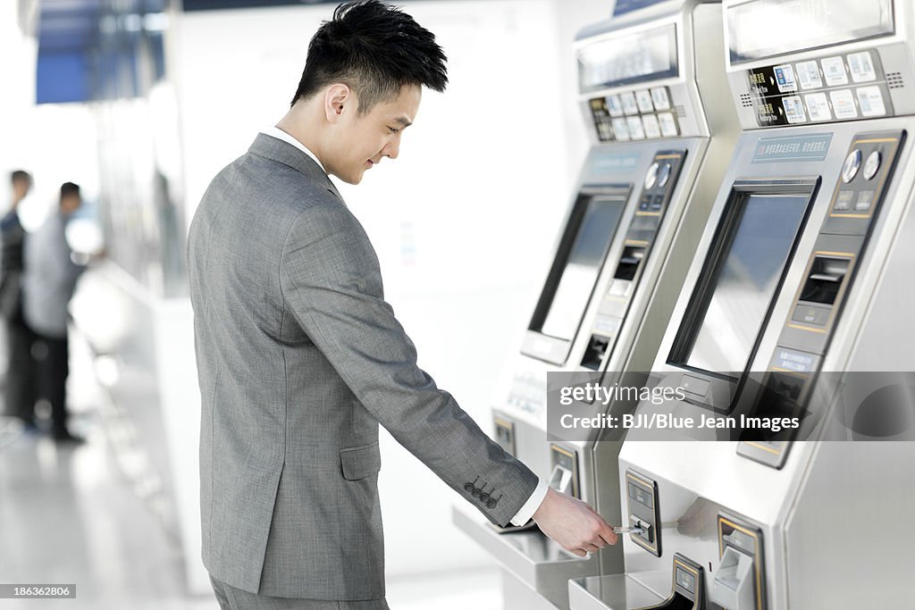 Young businessman using automatic ticket machine at subway station