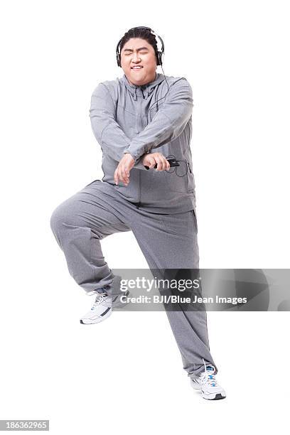 fashionable fat man listening to music and dancing - fat asian man stockfoto's en -beelden