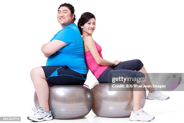 fat man and girlfriend sitting back to back on fitness balls - fat man slim woman couple stock pictures, royalty-free photos & images