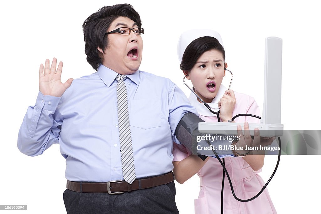 Nurse measuring blood pressure for overweight businessman