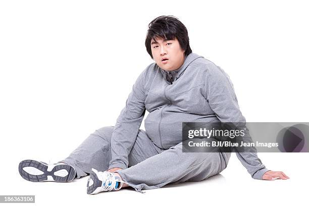 overweight man sitting on floor - guy in sweatpants fat stock pictures, royalty-free photos & images