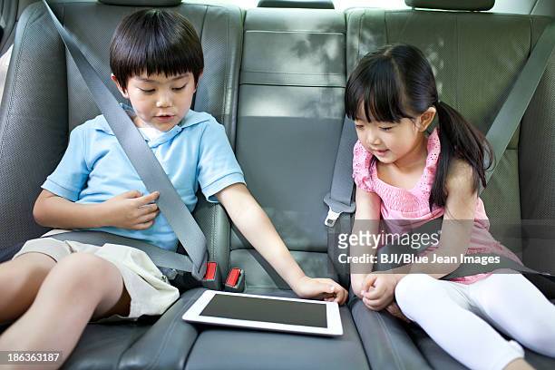 cute boy and girl playing digital tablet in car - child car tablet stock pictures, royalty-free photos & images