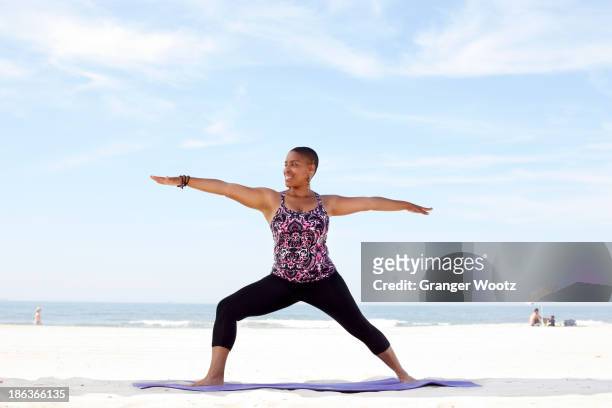 woman practicing yoga on beach - warrior position stock pictures, royalty-free photos & images