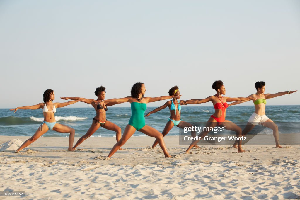 Women practicing yoga on beach