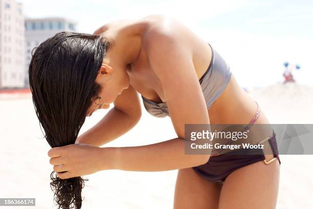 mixed race woman wringing out her hair on beach - human hair strand stock pictures, royalty-free photos & images