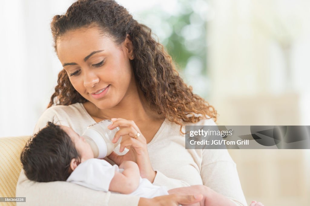 Hispanic mother bottle feeding infant son