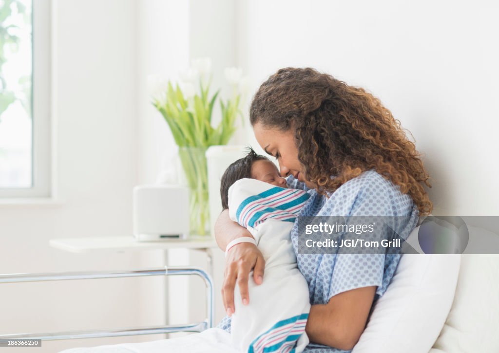 Hispanic mother holding newborn in hospital