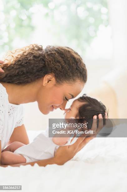 hispanic mother holding infant on bed - man and woman cuddling in bed stock-fotos und bilder