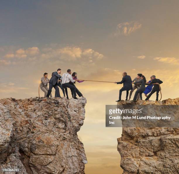 business people playing tug-of-war over canyon - team conflict stock pictures, royalty-free photos & images