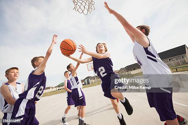 caucasian boys playing basketball on court - basketball net stock-fotos und bilder