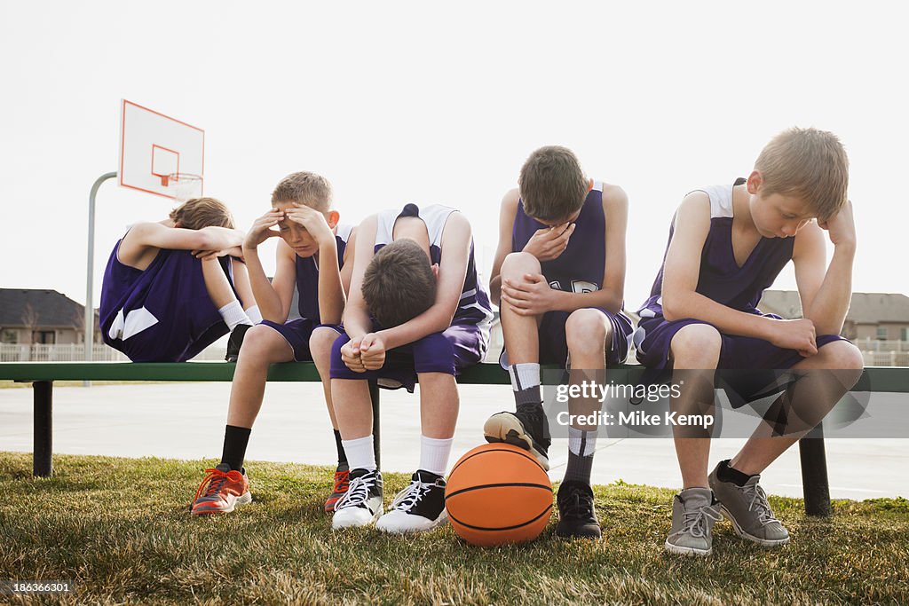 Caucasian basketball team sulking by court