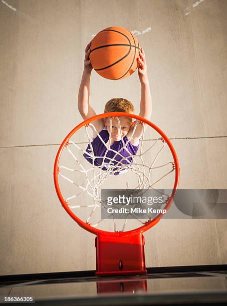 caucasian boy dunking basketball in hoop - shooting baskets stockfoto's en -beelden
