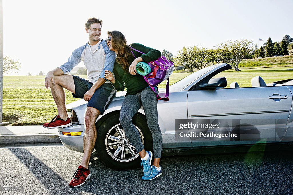 Couple wearing workout gear by convertible